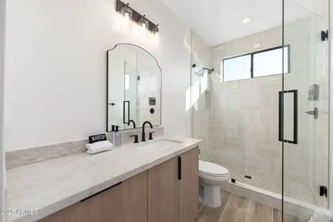 a bathroom with a granite countertop sink a toilet and shower