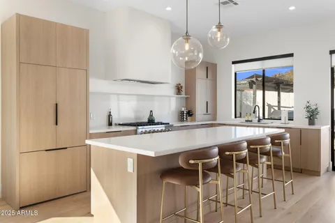 a kitchen with stainless steel appliances granite countertop a island a stove a refrigerator a sink a dining table and chairs with wooden floor