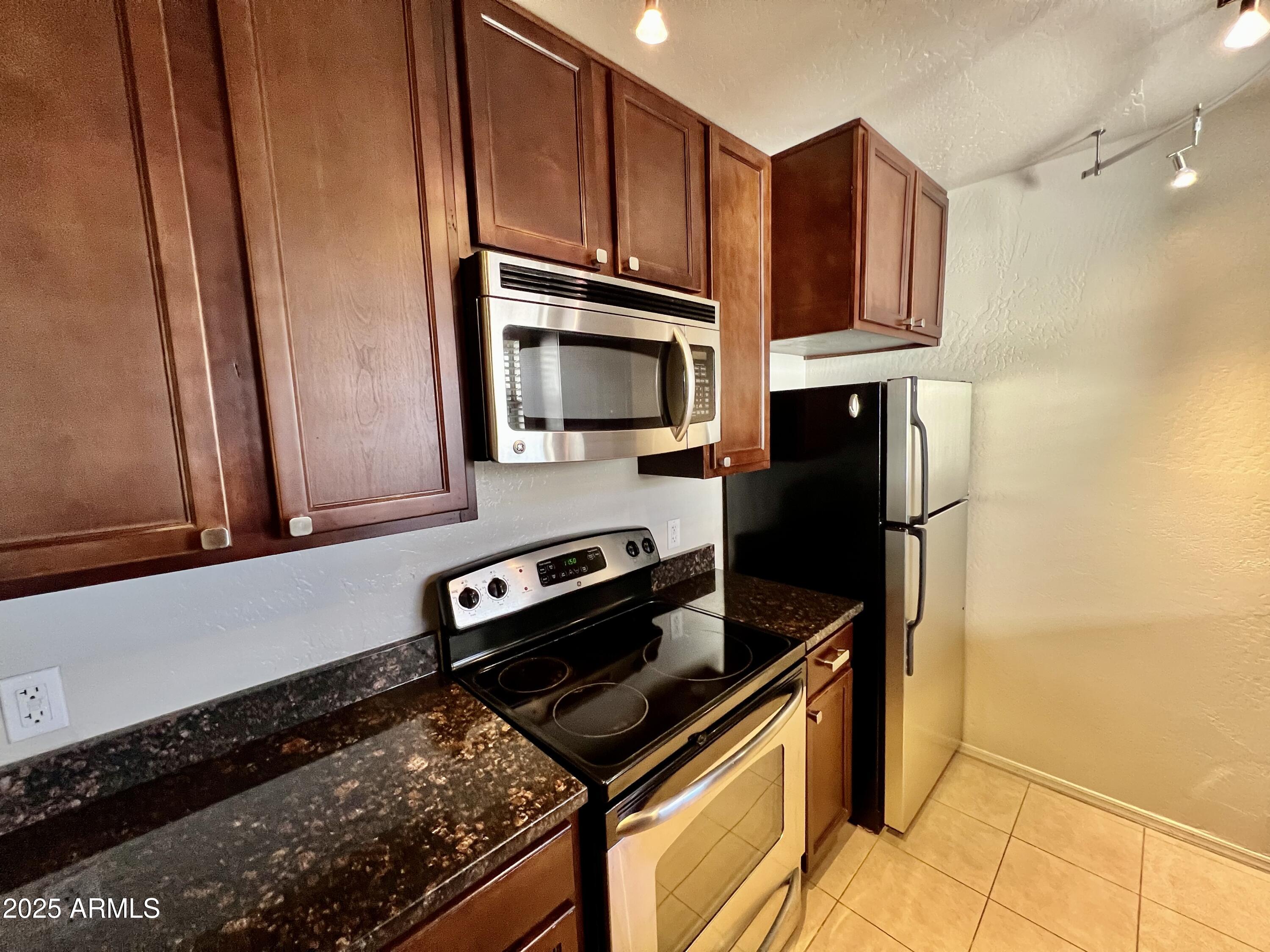 14145 North 92nd Street, Unit 2101 Scottsdale, AZ 85260 - Photo 9 of 30 a kitchen with stainless steel appliances a stove a microwave and a refrigerator