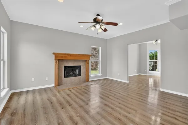 a view of an empty room with wooden floor fireplace and a window