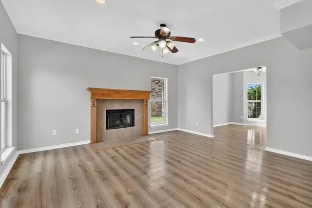 a view of an empty room with wooden floor fireplace and a window