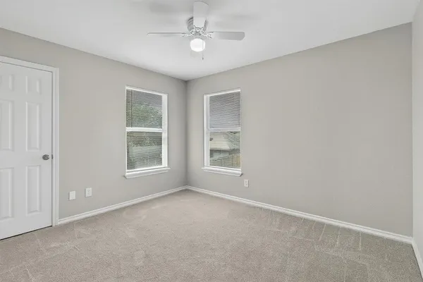 an empty room with windows and fan