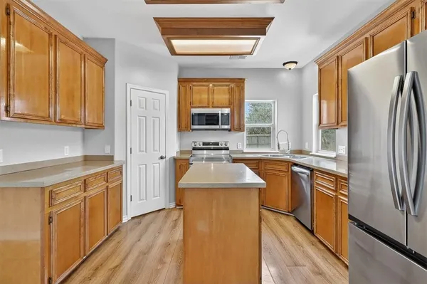 a kitchen with stainless steel appliances granite countertop a refrigerator a sink dishwasher a stove with wooden floor and cabinets