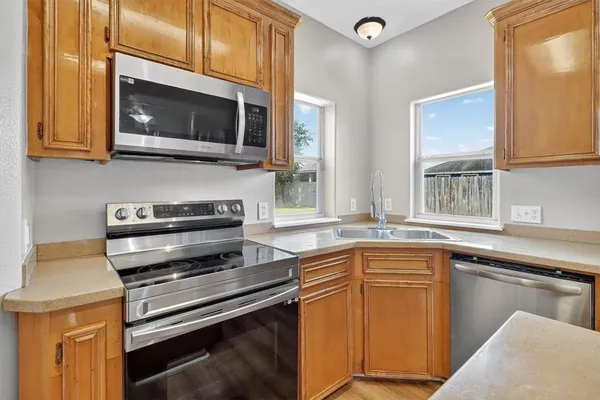 a kitchen with stainless steel appliances a stove microwave and sink