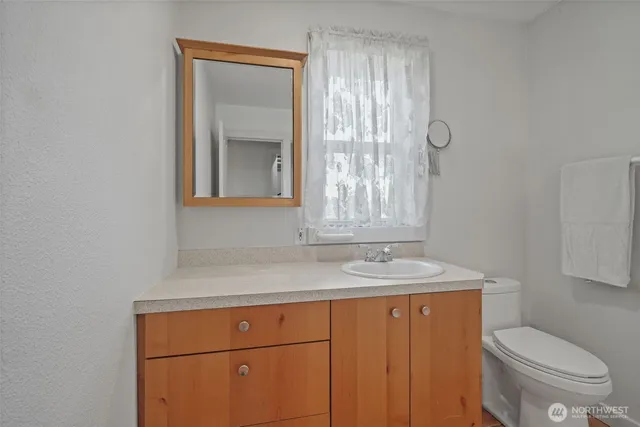 a bathroom with a granite countertop sink toilet and mirror