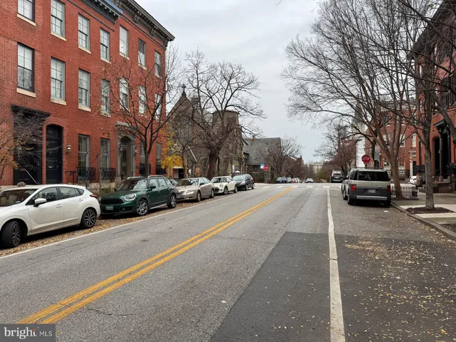 a city street lined with buildings and cars parked on the roadside