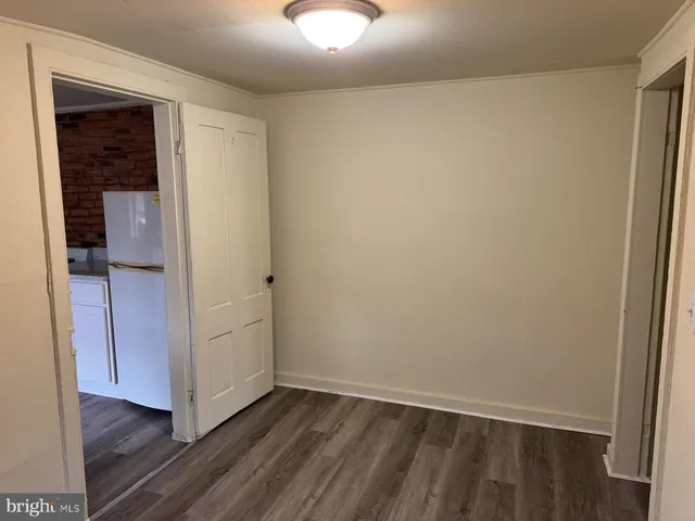 an empty room with wooden floor closet and windows