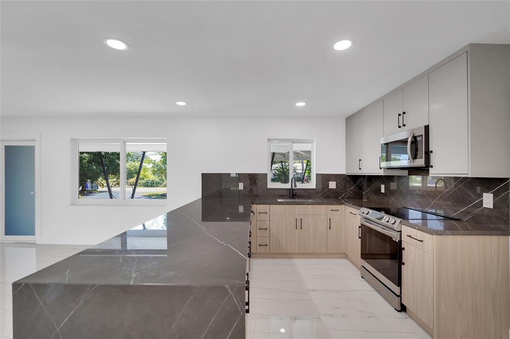 121 Southeast 8th Street Pompano Beach, FL 33060 - Photo 4 of 14 a large kitchen with stainless steel appliances granite countertop a sink counter space cabinets and a couch