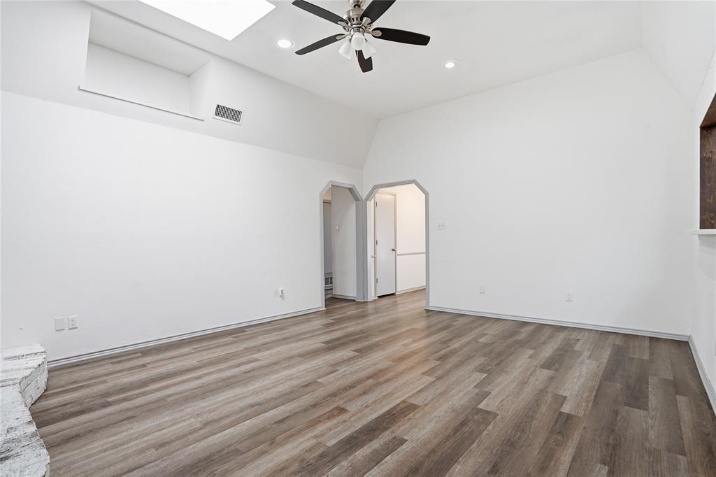 4612 Applewood Road Fort Worth, TX 76133 - Photo 23 of 39 Empty room with arched walkways, light wood-type flooring, high vaulted ceiling, ceiling fan, and a skylight