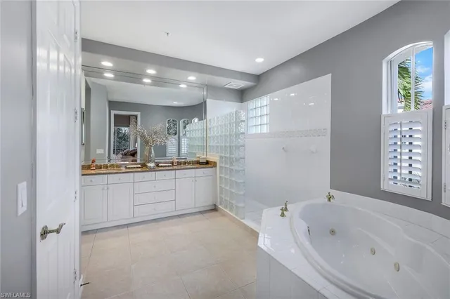a bathroom with a bathtub a double vanity sink and mirror