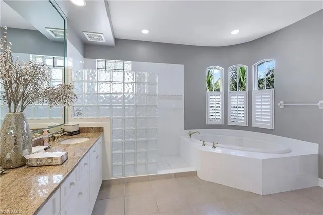 a bathroom with a granite countertop bathtub sink vanity and window