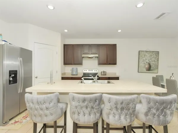 a kitchen with stainless steel appliances granite countertop a stove a sink a refrigerator a dining table and chairs
