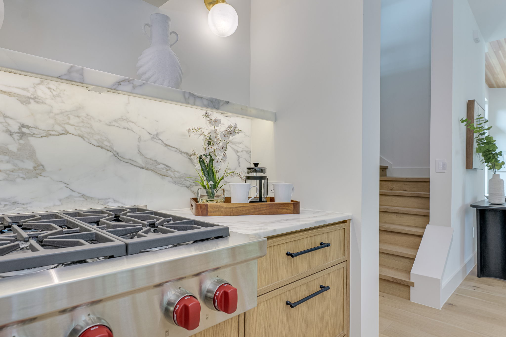 405 Honeycomb Ridge Austin, TX 78746 - Photo 7 of 15 Culinary adventures await in this kitchen, boasting a sleek range and marble backsplash, seamlessly flowing into a naturally illuminated living space.