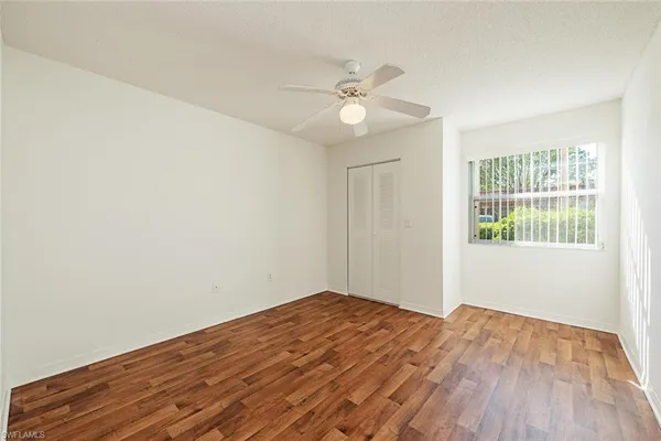a view of empty room with wooden floor and fan