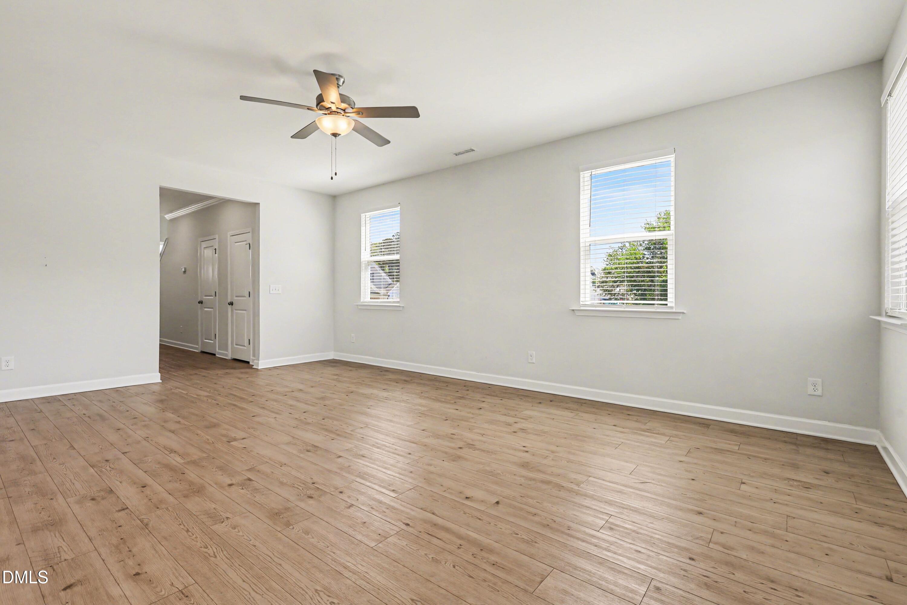 90 Rigsby Avenue Four Oaks, NC 27524 - Photo 17 of 43 an empty room with wooden floor chandelier fan and windows
