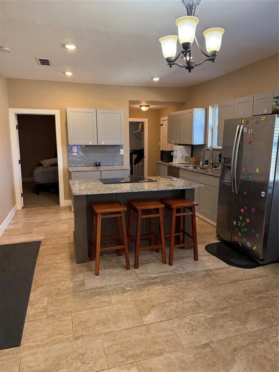 809 South Wine Street Gainesville, TX 76240 - Photo 10 of 33 Kitchen with stainless steel appliances, a kitchen breakfast bar, pendant lighting, a kitchen island, and tasteful backsplash