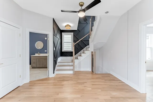 an empty room with wooden floor fan and windows