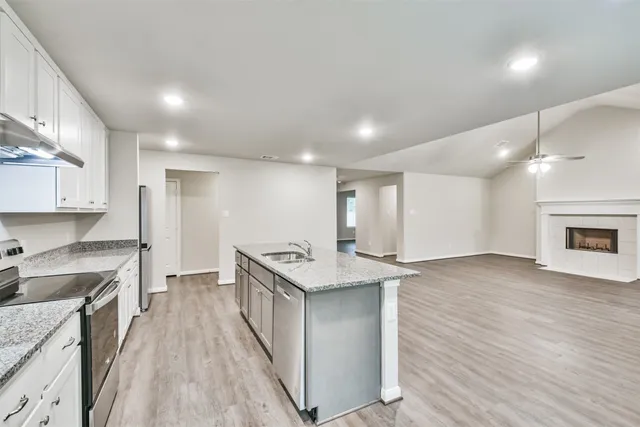 a kitchen with stainless steel appliances granite countertop a sink stove and a wooden floors