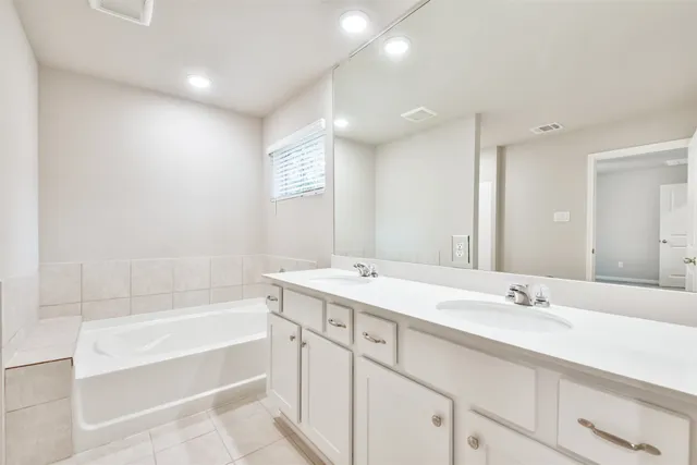 a bathroom with a tub a sink and mirror