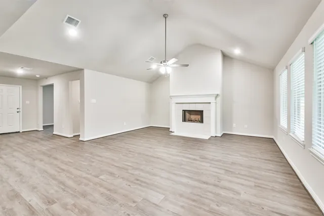 a view of a livingroom with a fireplace a ceiling fan and windows