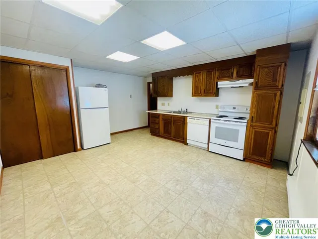 a large kitchen with stainless steel appliances granite countertop a stove refrigerator and a sink