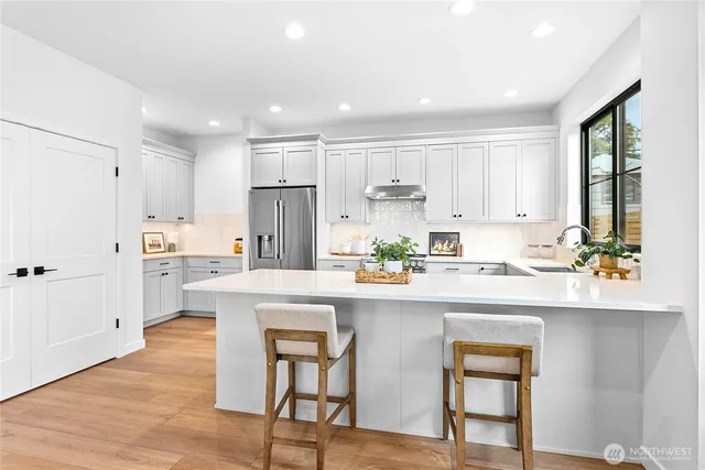 a kitchen with stainless steel appliances white cabinets and wooden floor