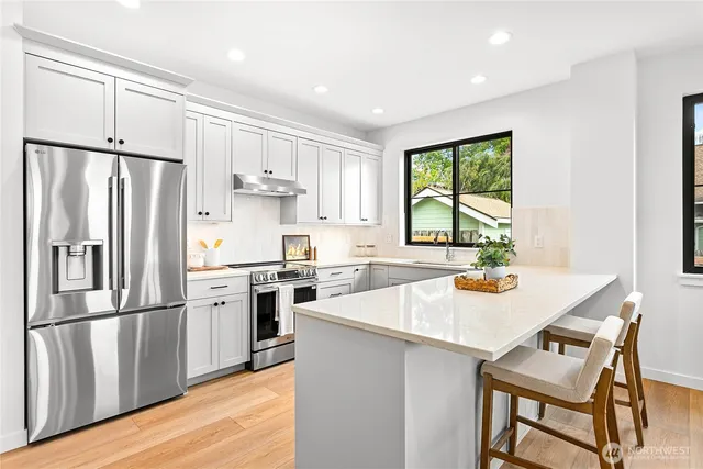 a kitchen with a refrigerator a stove a sink and a dining table with wooden floor