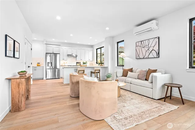 a living room with furniture and a kitchen view with wooden floor