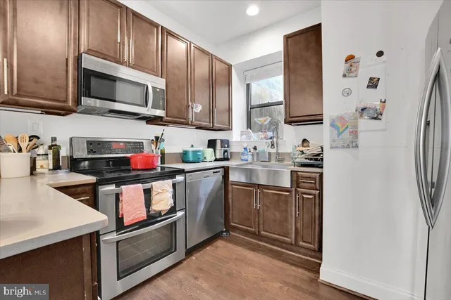 a kitchen with stainless steel appliances granite countertop a refrigerator a sink and white cabinets