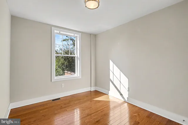 a view of an empty room with wooden floor and windows
