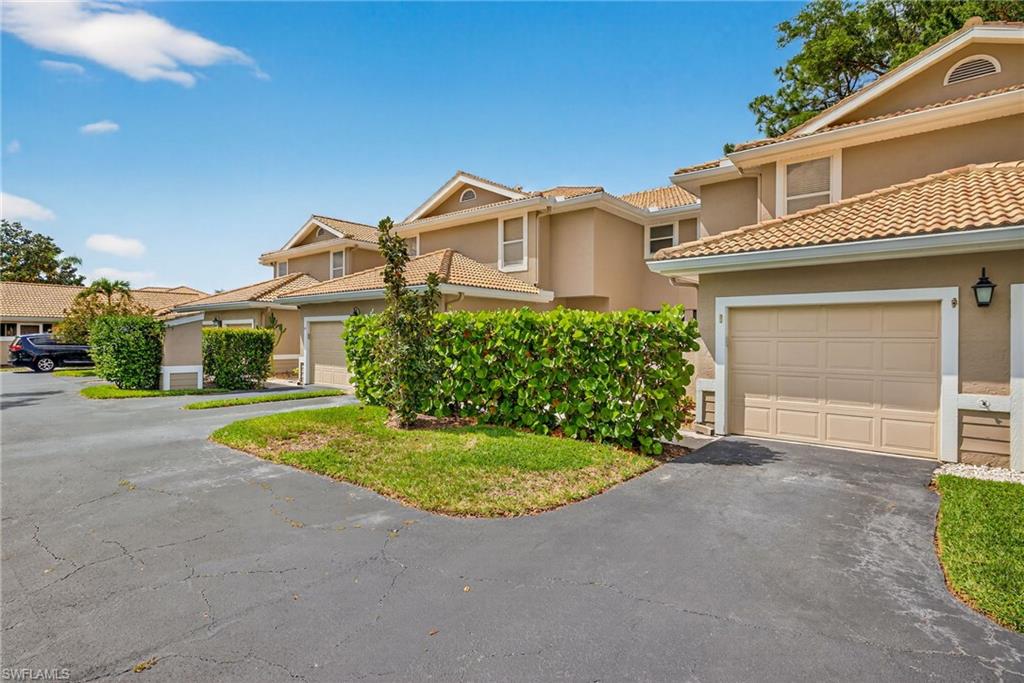 290 Emerald Bay Circle, Unit L7 Naples, FL 34110 - Photo 18 of 22 a front view of a house with a yard and garage