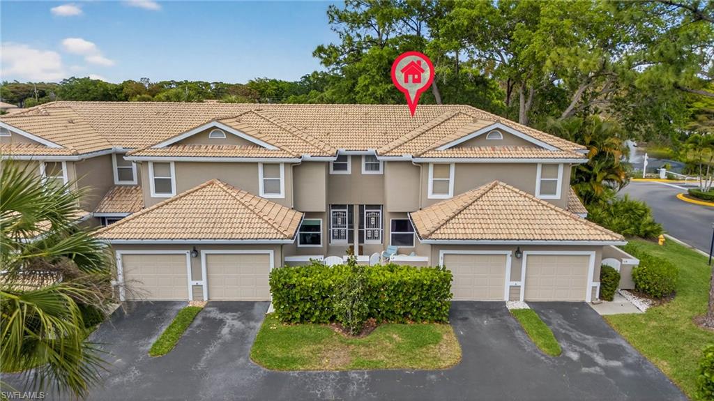 290 Emerald Bay Circle, Unit L7 Naples, FL 34110 - Photo 2 of 22 a front view of a house with a yard and garage