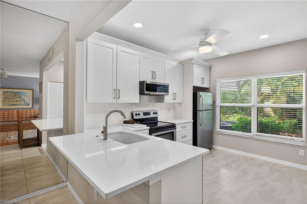 290 Emerald Bay Circle, Unit L7 Naples, FL 34110 - Photo 5 of 22 a kitchen with a sink a counter top space and stainless steel appliances