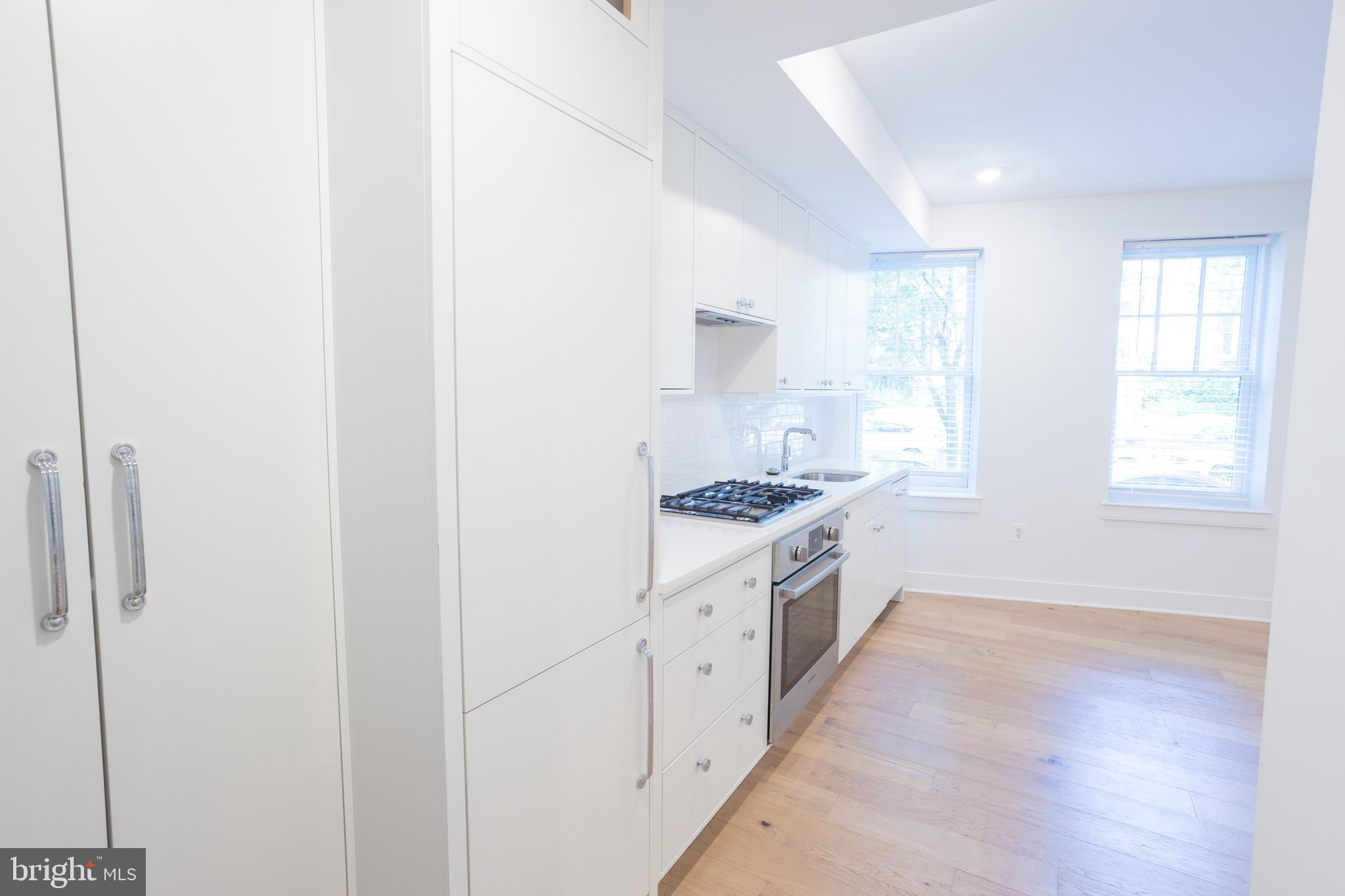 2869 28th Street Northwest, Unit 204 Washington, DC 20008 - Photo 13 of 19 a large white kitchen with granite countertop a large window and a sink