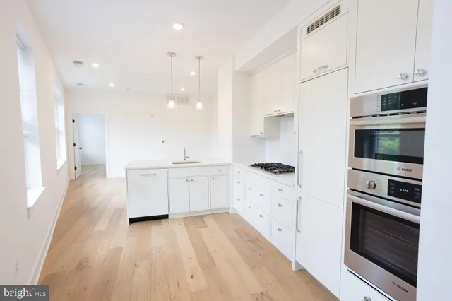 a kitchen with stainless steel appliances a stove a microwave and white cabinets