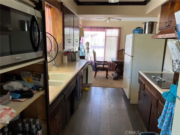 a kitchen with stainless steel appliances granite countertop a refrigerator a stove a sink dishwasher and a dining table with wooden floor