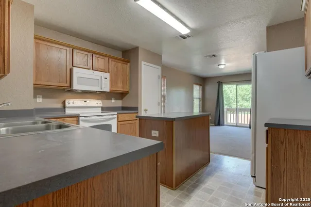 a kitchen with stainless steel appliances granite countertop a refrigerator a sink dishwasher a stove and white countertops with wooden floor