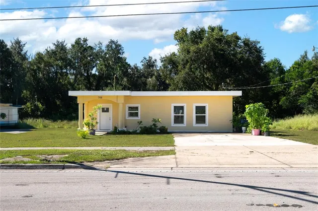 a front view of a house with a yard and trees