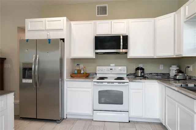 a kitchen with stainless steel appliances granite countertop white cabinets a sink a stove and a refrigerator