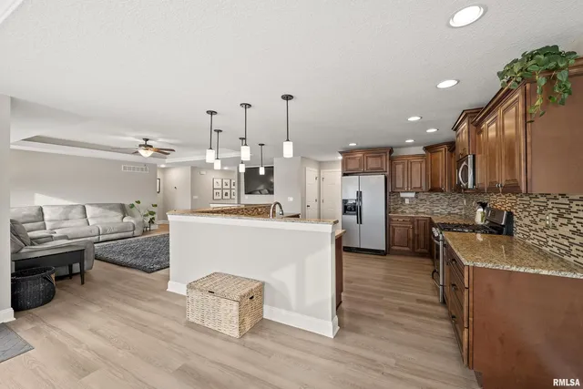a kitchen with stainless steel appliances granite countertop a sink a stove and a wooden floors