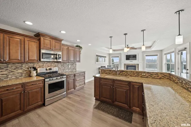 a kitchen with stainless steel appliances kitchen island granite countertop a table chairs and a refrigerator