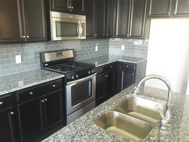 a kitchen with granite countertop a sink a stove and cabinets