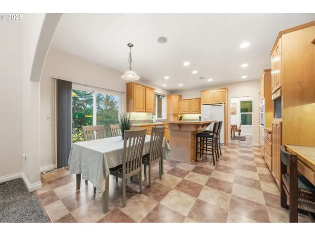 a dining hall with stainless steel appliances kitchen island granite countertop a table chairs and a oven