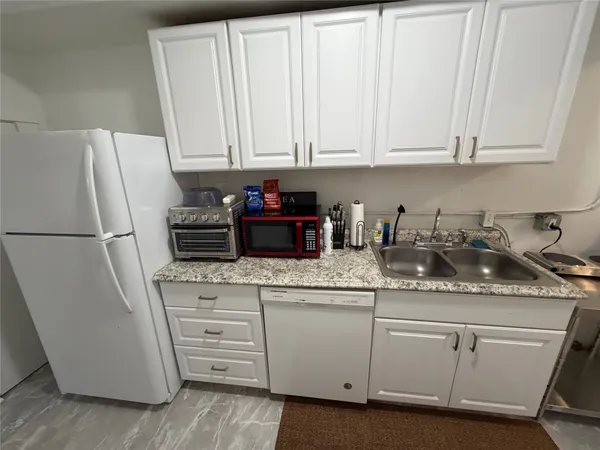a kitchen with white cabinets and refrigerator