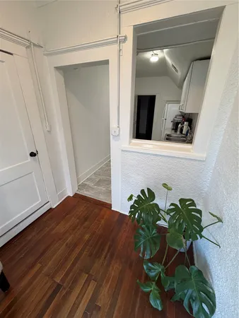 a view of a hallway with wooden floor and a potted plant