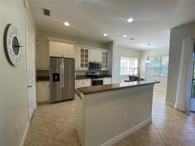 a kitchen with stainless steel appliances granite countertop a refrigerator a stove a sink and a microwave