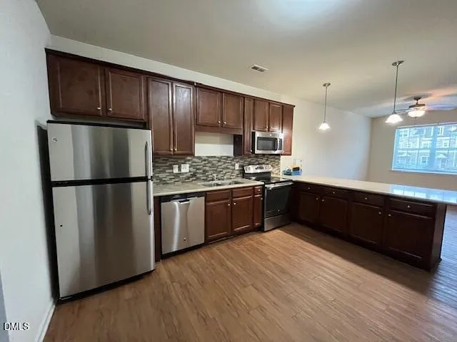 a kitchen with stainless steel appliances granite countertop a refrigerator a sink dishwasher a stove top oven a refrigerator and cabinets