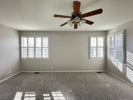 a view of a livingroom with a ceiling fan and windows