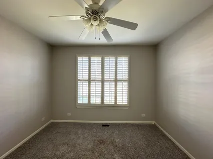 an empty room with a window and a fan