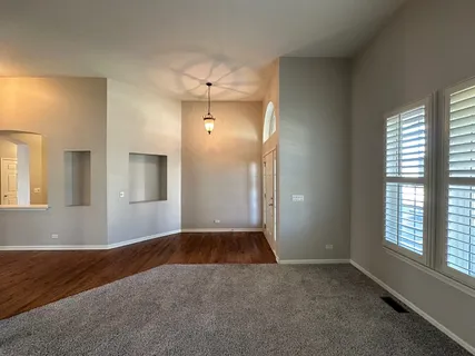 an empty room with windows and chandelier fan